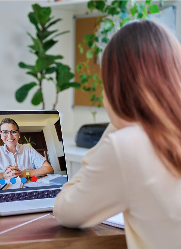 A person sits at a desk having a video call with another person.